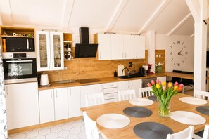 Een moderne keuken met witte kastjes, een houten aanrechtblad en een eethoek met een tafel voor vier personen.