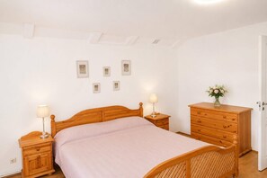 Ein Schlafzimmer mit einem hölzernen Bett, Nachttischen mit Lampen, einem Schminktisch und gerahmten Bildern an der Wand.