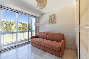 Una stanza con un'ampia porta-finestra in vetro, un divano, una lampada da terra e un quadro appeso al muro.