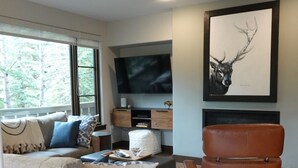 En stue med sofa, sofabord, læderlænestol, fjernsyn og loftventilator.