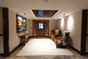 A hallway with a large painting, a wooden bench, a reception desk, and a door leading to another room. -  REMODELED 2 BEDROOM CONDO  PINECONE IN ARROWHEAD CLOSE TO LIFT (Edwards)