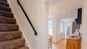Eine Treppe führt zu einem Essbereich mit einem Holztisch und Stühlen.