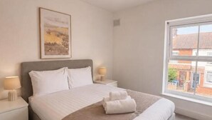 Ein Hotelzimmer mit einem großen Bett, Nachttischlampen, einem Fenster und einem Bild an der Wand.