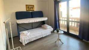 A room with a bunk bed, a small table, and a window with curtains. - Daluef Alloggi - Loft 1 (Assemini)