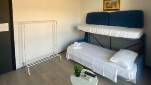 A room with a bunk bed, a small round table with a plant, and a wall-mounted air conditioner. - Daluef Alloggi - Loft 1 (Assemini)