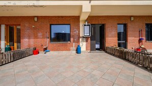 A courtyard with a brick wall, a window, a door, and a water heater. - Daluef Alloggi – Room 4 (Assemini)