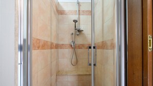 A glass-enclosed shower stall with a handheld showerhead and a wall-mounted faucet. - Daluef Alloggi – Room 4 (Assemini)