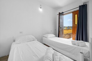 A room with two single beds, a window with curtains, and a view of the outside. - Daluef Alloggi – Room 4 (Assemini)