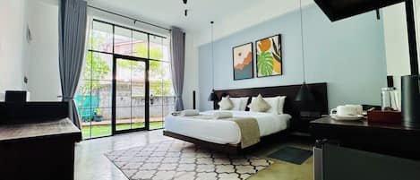 A hotel room with a bed, a desk, a chair, a ceiling fan, and a view of the outdoors.