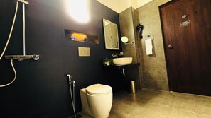 Un baño con inodoro, lavabo, espejo y ducha.