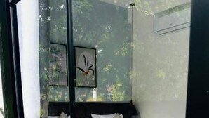 Un dormitorio con cama, mesita de noche y ventana con vista a árboles.