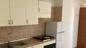 Una cocina con armarios blancos, un fregadero, una estufa y un refrigerador.