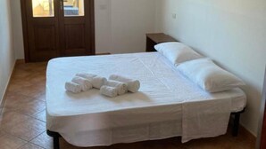 Un dormitorio con cama, mesita de noche, equipo de aire acondicionado y puerta que da a un espacio exterior.