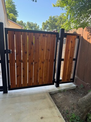A wooden gate with a black frame, leading to a concrete pathway.