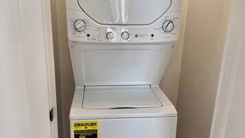 Lavadora y secadora apilables blancas con etiqueta ENERGYGUIDE, ubicadas en un pasillo estrecho.