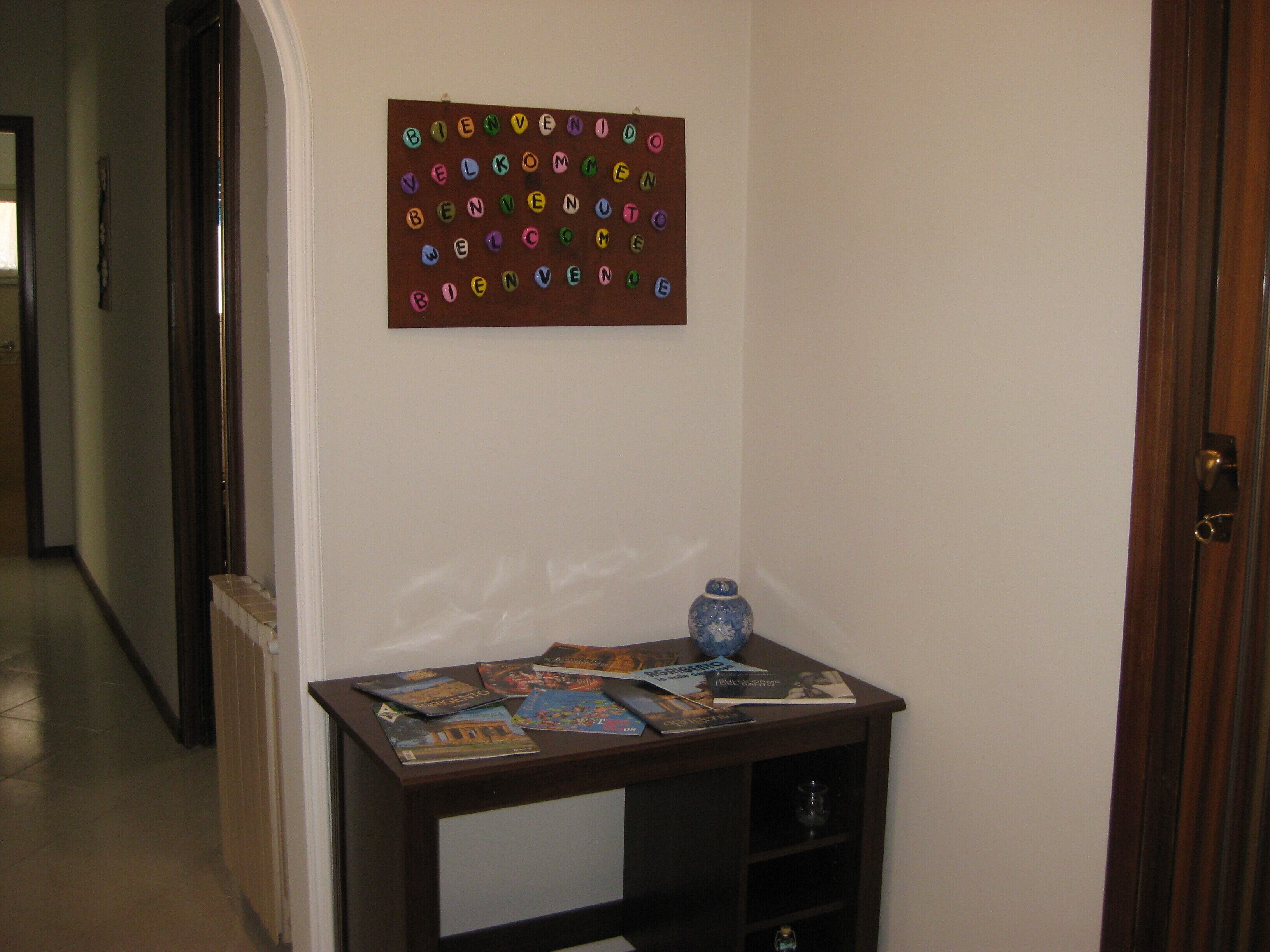 Een hal met een houten tafel waarop tijdschriften en een decoratieve blauwe vaas staan.