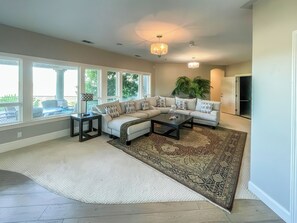 A modern living room with a sectional sofa, a coffee table, and a large window. - Serrano Village Villa (El Dorado Hills)