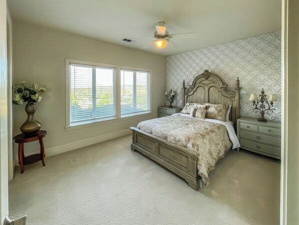 A bedroom with a large bed, a nightstand, a lamp, and a vase with flowers. - Serrano Village Villa (El Dorado Hills)
