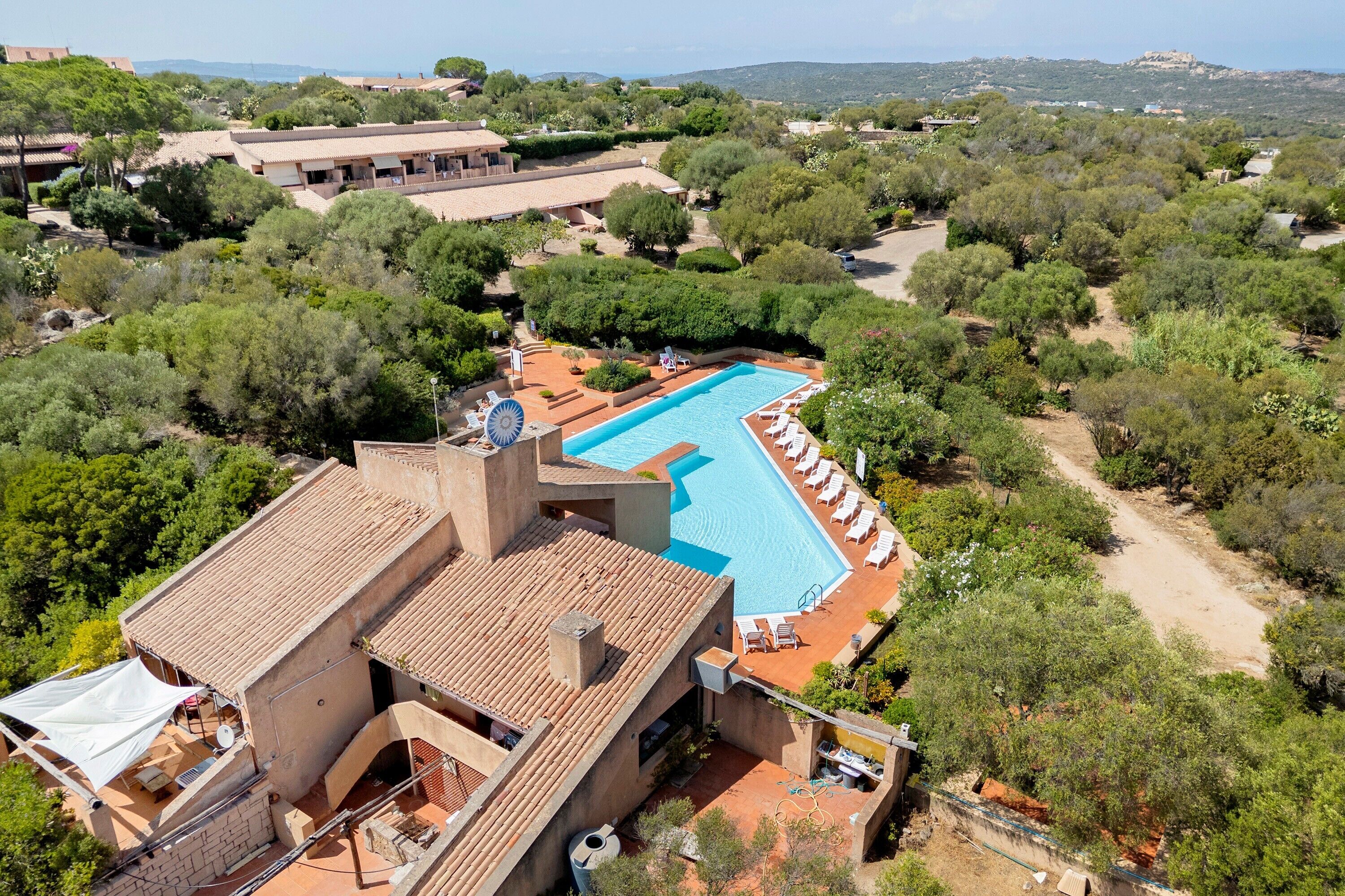 A resort with a swimming pool, lounge chairs, and a view of the surrounding landscape.