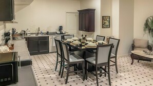 A modern kitchen with dark cabinets, a dining table set for four, and a ceiling fan. - Serrano Village Villa - El Dorado Hills (El Dorado Hills)