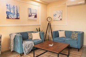 Un salon avec deux canapés, une table basse et des œuvres d’art murales.