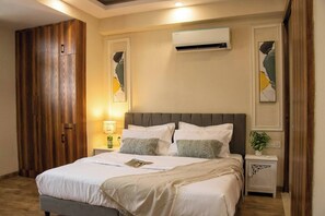 A bedroom with a bed, bedside tables, an air conditioning unit, and a wardrobe. - 402 - Designer 1BR Retreat - Golf Course Rd (Gurugram)