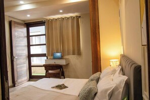 A hotel room with a bed, a desk with a laptop, a chair, and a window with curtains. - 402 - Designer 1BR Retreat - Golf Course Rd (Gurugram)