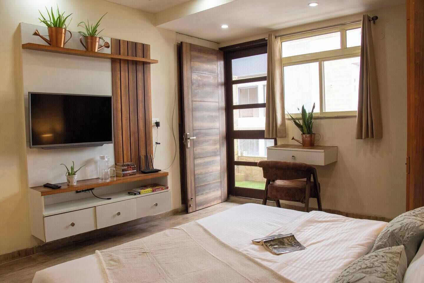 Ein Schlafzimmer mit einem Bett, einem Fernseher, einem Holzschrank, einem Sessel und einem Fenster.