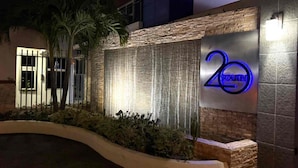 Fachada de edificio con pared de piedra, fuente de agua y letrero de neón que indica '20 SOUTH'.