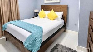 Un dormitorio con cama, mesita de noche, lámpara y ventana.