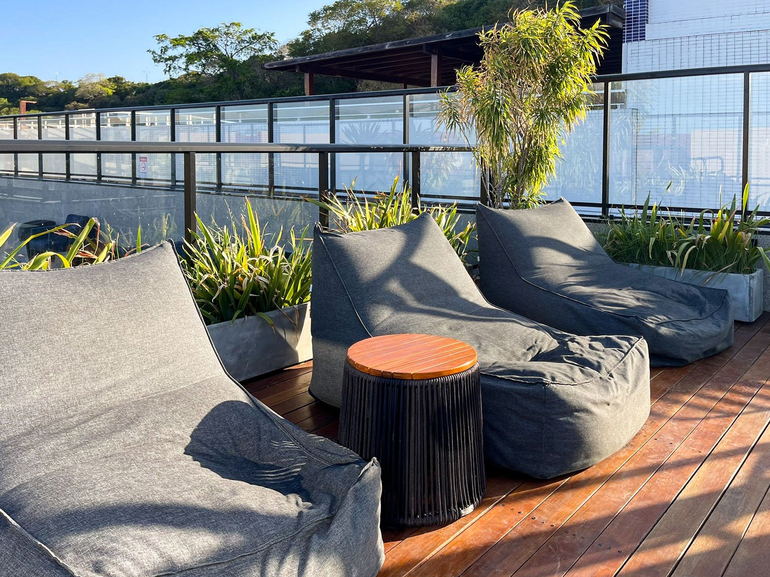 A rooftop terrace with seating, planters, and a view of the city.