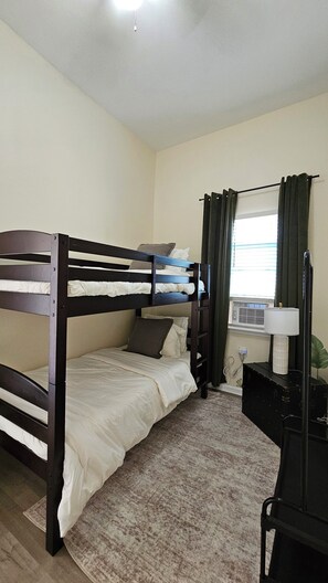 Quarto com beliche, escrivaninha e abajur.