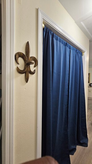 Ein Zimmer mit einer Tür, die ein dekoratives Metallzeichen und einen blauen Vorhang zeigt.
