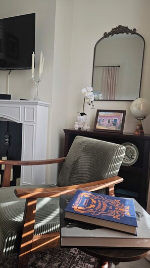 A room with a wooden chair, a table with books, a globe, and a mirror on the wall. - 3-Bedroom Creole Cottage Near French Quarter (New Orleans)