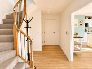 A staircase with wooden handrails and a coat rack, leading to a door and a kitchen area. - Bright and Spacious 2BDR Flat Westfield Stratford (Greater London)