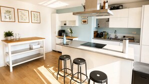 Una cocina moderna con armarios blancos, una isla central con taburetes, un microondas y una estufa.