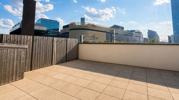 Una terraza en la azotea con vistas al horizonte de una ciudad, incluyendo edificios modernos y un cielo despejado.