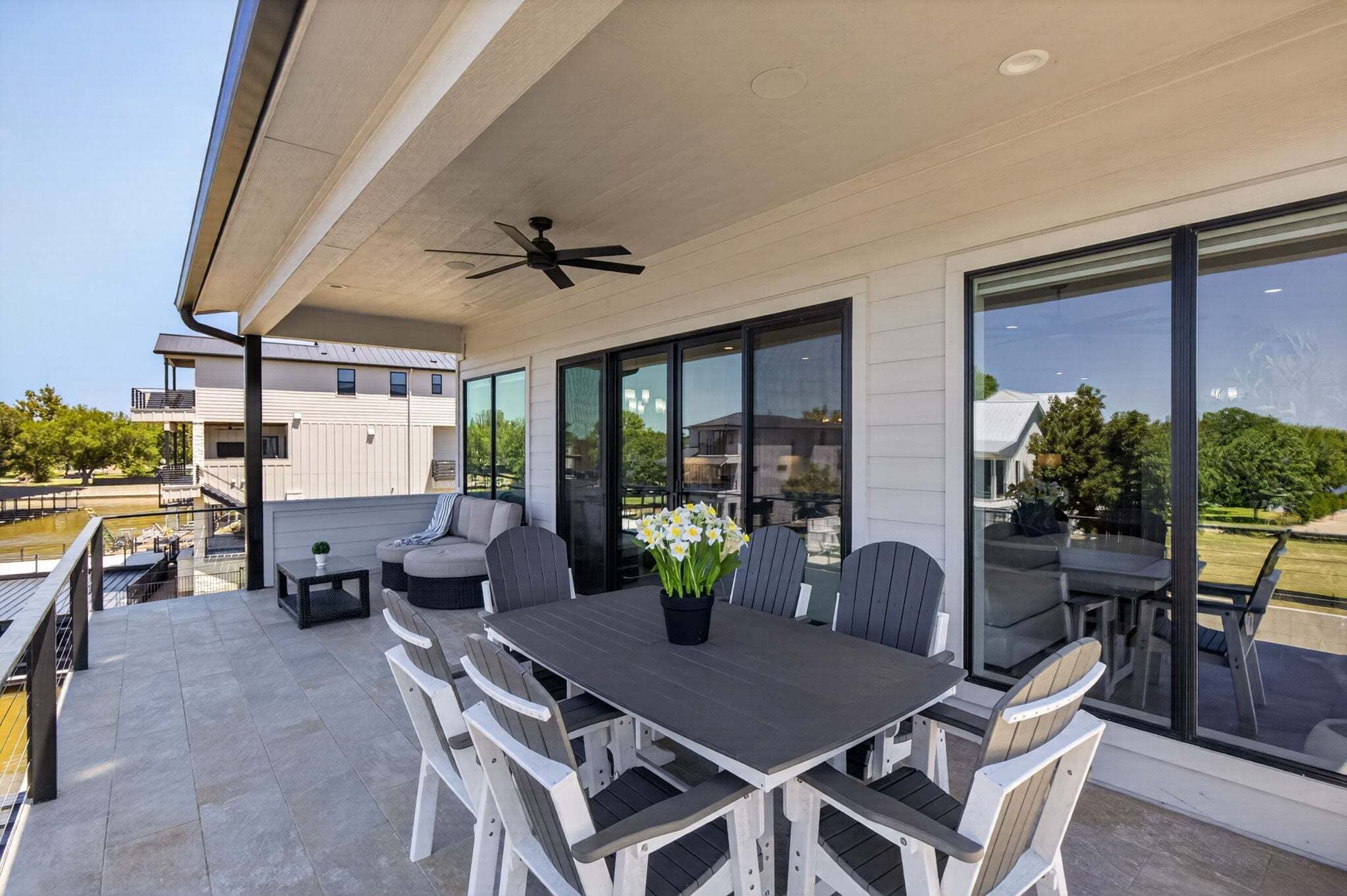 Une terrasse extérieure avec une table à manger, des chaises et un ventilateur de plafond.