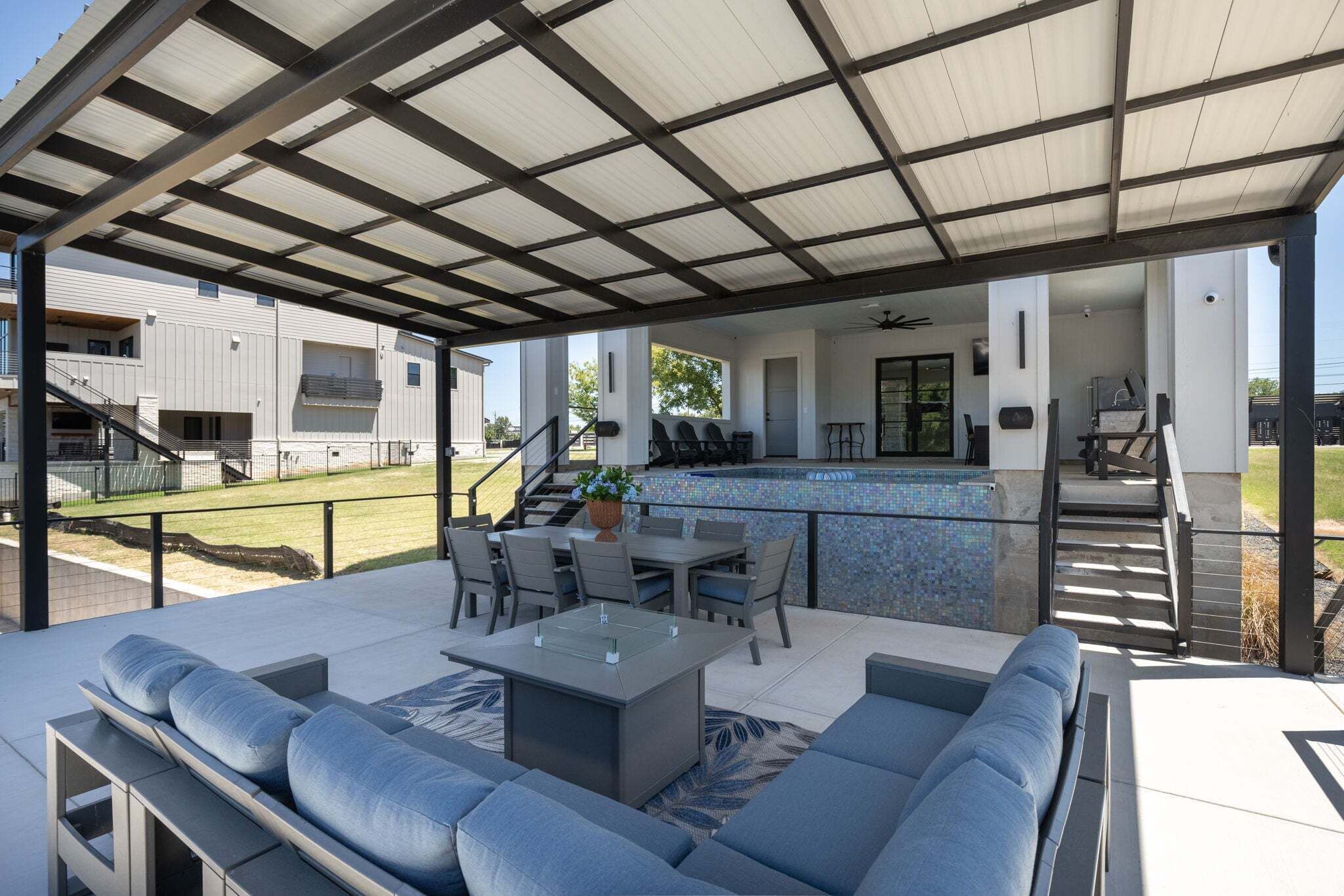 Un patio techado con mobiliario, comedor y piscina.