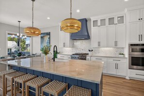 A modern kitchen with a large island, white cabinetry, and stainless steel appliances. - *New* The Marbella on LBJ | Private Pool, Boat Slips & Lift, Sleeps 19 🌅 (Kingsland)
