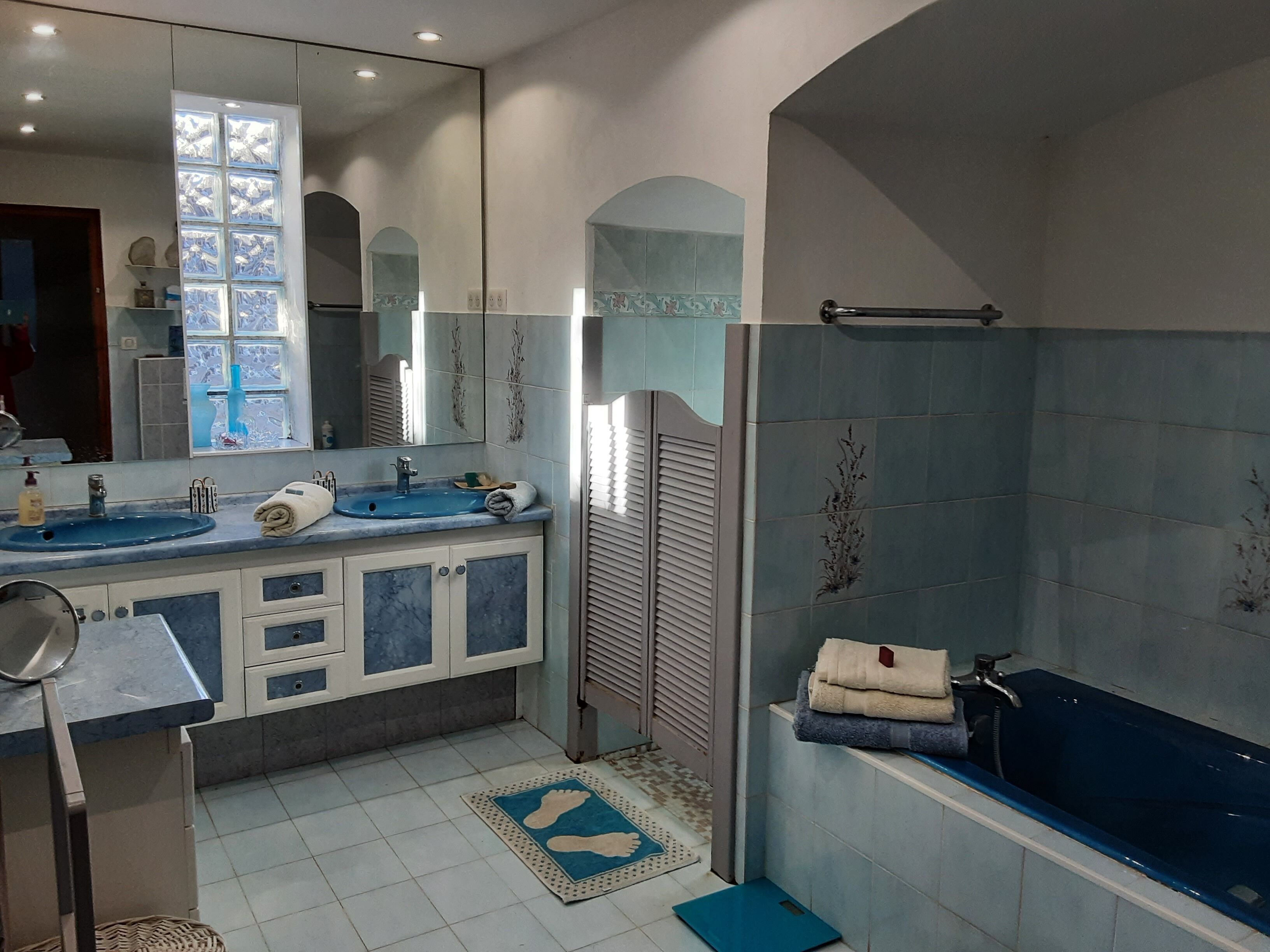 Een badkamer met twee wastafels, een spiegel, een douche en een bad.