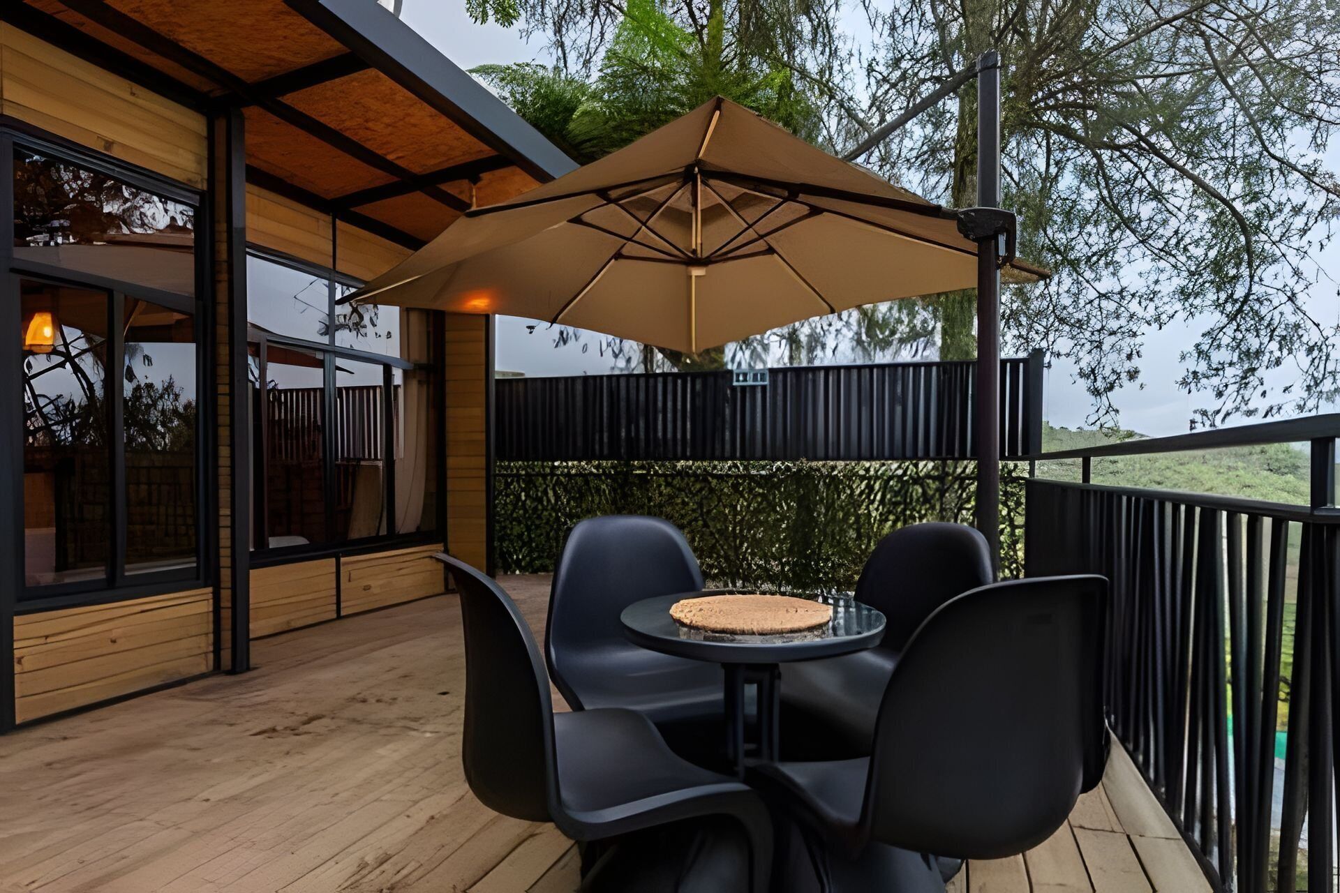 An outdoor patio with a table and chairs, a large umbrella, and a view of the surrounding landscape.