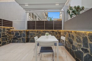 Un patio al aire libre con un muro de piedra, una mesa blanca y sillas.