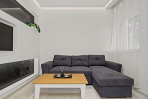 Una sala moderna con un sofá modular, una mesa de centro, un televisor y una planta.