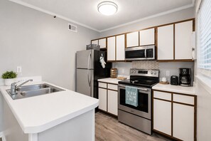 A modern kitchen with a stainless steel refrigerator, microwave, stove, and sink. - Beachfront 2BR, Stunning Gulf Views, Indoor/Outdoor Pools, Hot Tub, Tennis Court (Gulf Shores)