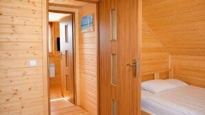 Een houten kamer met een bed, een deur en een raam.