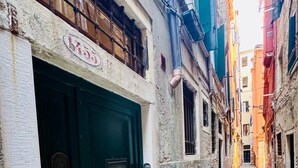 A narrow alleyway with a green door, stone pavement, and buildings on either side. - Rialto Vacations with Air Conditioning and Shared Kitchen (Venice)