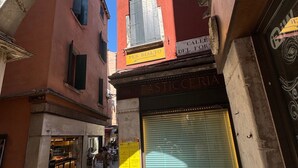 An urban street with a closed shop, a visible sign for 'Dolci Tipici Veneziani,' and a stone archway. - Rialto Vacations with Air Conditioning and Shared Kitchen (Venice)