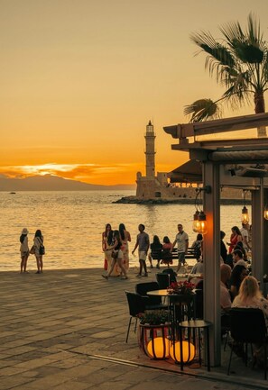 Ein Restaurant am Wasser mit Außenbereich, das auf das Meer und einen historischen Leuchtturm blickt.