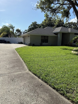 A residential house with a front yard, driveway, and a white fence. - Live your best Florida life! 
Charming 3 bedroom in The Chain of Lakes region. (Winter Haven)